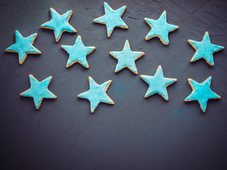 Festive, fragrant cookies in the shape of the stars, covered with turquoise glaze on a dark,...