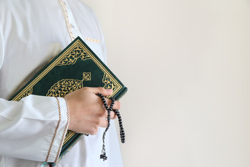 Hand of muslim man carry holy Quran . Quran - holy book of Muslims around the world. Concept of...