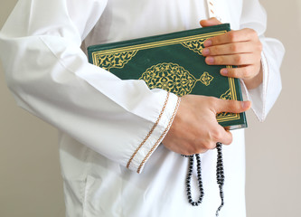 Hand of muslim man carry holy Quran . Quran - holy book of Muslims around the world. Concept of Quran