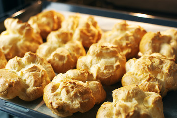 Homemade profiteroles in the oven. Process of baking cookies, French dessert, confectionery background. 