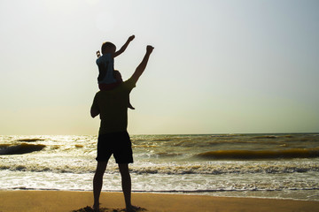 Fototapeta premium Father and son playing on the beach at the sunset time. Concept of friendly family