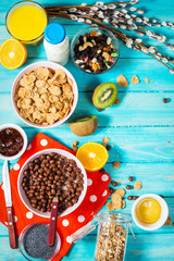 Healthy breakfast with bowl of cereal, orange juice, granola, milk, jam and fruits on blue wood background. Balanced diet.