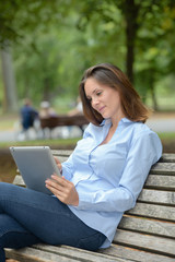 Lady on park bench looking at tablet