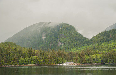 Bergige K&uuml;stenlandschaft Canadas, kleiner flacher Wasserfall f&uuml;hrt in den Stom der Inside Passage.