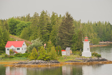 Canadas Westen, kleine Insel mit Leuchtturm und Haus im Vordergrund in der Inside Passage, bewaldete H&uuml;gellandschaft.