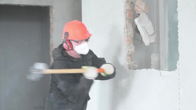 demolition work and rearrangement. worker with sledgehammer destroying wall