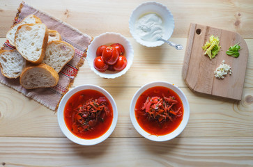 Two plates of soup. Ukrainian traditional borsch. Russian vegetarian red soup in white bowl on wooden background. Top view.
