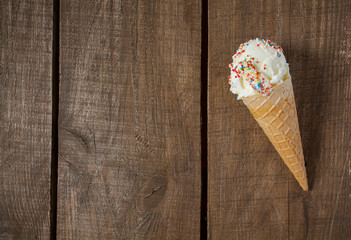 vanilla ice cream in waffle cones over wooden surface