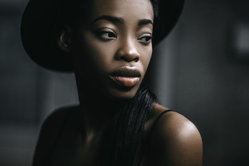 Portraite photo of adorable african woman. Pretty girl smiling and take her hand to hat on the head.