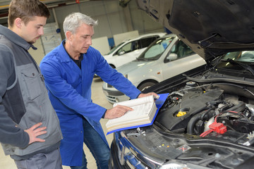 student with instructor repairing a car during apprenticeship