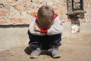 Fototapeta premium A Sad and lonely boy beside brick wall