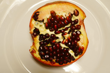 Half of pomegranate on the white plate.