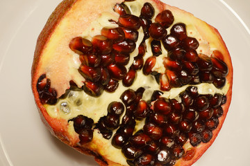 Half of pomegranate on the white plate.