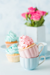 Blue pastel banner with decorated cupcakes, cup of coffe with milk and bouquet of pink roses.