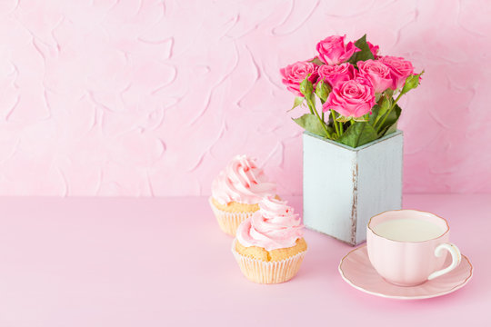 Pink pastel horisontal banner with decorated cupcakes, cup of coffe with milk and bouquet of pink roses.
