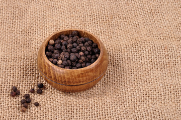 pepper not ground in a wooden bowl on a ragged background.