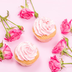 Cupcake with pink cream decoration and roses on pink pastel background.