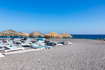Obraz premium beach with umbrellas and deck chairs by the sea in Santorini