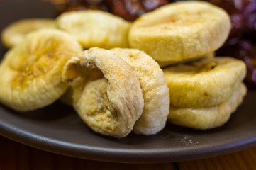 dried dates and figs in a ceramic plate on a wooden table