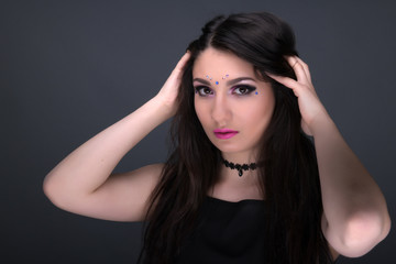 Close up face. Young arabic woman in black sexy dress, isolated on gray background