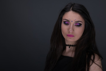 Close up face. Young arabic woman in black sexy dress, isolated on gray background
