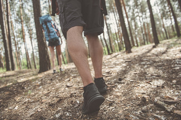 Active lifestyle. Low angle close up of feet of young energetic tourist who is going across forest....