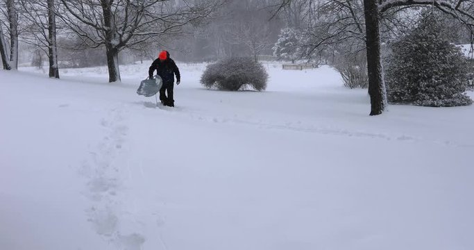 Mature man trying to sled outdoor on snowy winter afternoon.