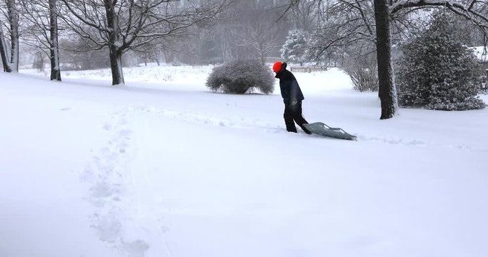 Man hauling sled up hill outdoor on snowy winter afternoon.