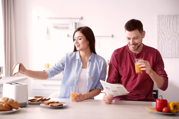 Young couple having breakfast with toasts in kitchen