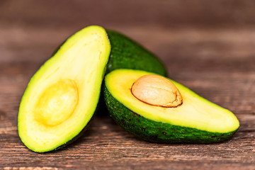 Avocados cut and whole on a wooden background