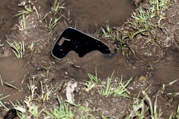 Mobile phone in brown mud with water