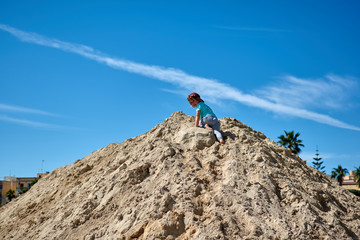 A child climbs up a mountain of sand on the beach