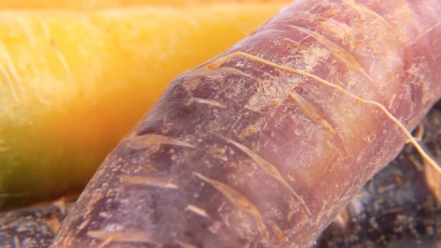 A bunch of carrots (not the usual variety, yellow and violet colors) on a rotating surface. Above extreme close-up shot.
