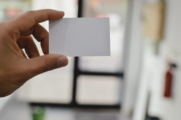 Close up on hand of a businessman showing business card office space background