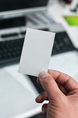 Close up on hand of a businessman showing business card office space background