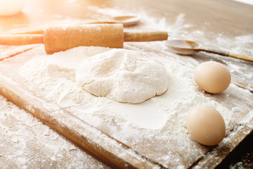 Baking ingredients. Bowl, eggs, flour, eggbeater, rolling pin and eggshells on black chalkboard from above.