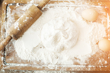 Baking ingredients. Bowl, eggs, flour, eggbeater, rolling pin and eggshells on black chalkboard from above.