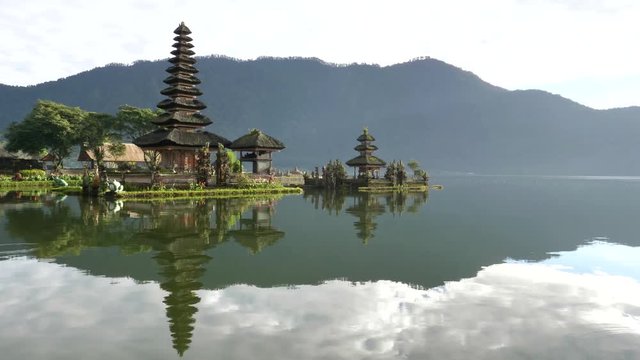 an early morning panning shot of pura danu bratan temple and a calm lake on the island of bali, indonesia