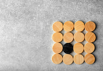 One black circle among wooden ones on light background. Difference and uniqueness concept
