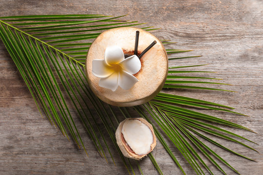 Beautiful composition with fresh green coconut and palm leaf on wooden background