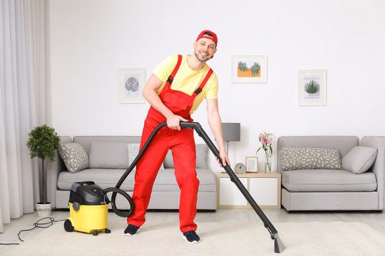 Mature man hoovering carpet with vacuum cleaner in living room