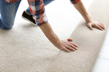 Man rolling out new carpet flooring in room