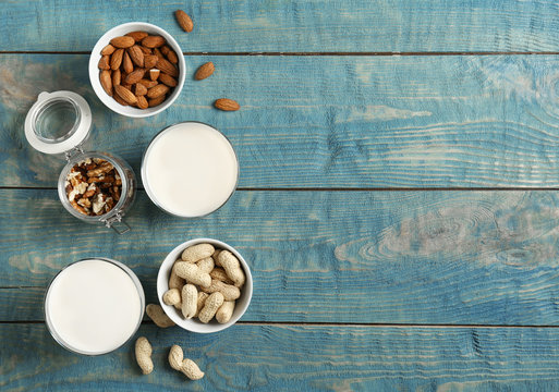 Glasses with different types of milk and nuts on wooden background