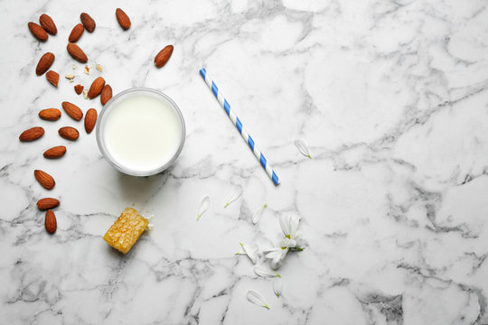 Glass with milk, nuts and honeycomb on light background, flat lay