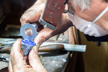 Jeweler engraving diamonds on a ring.