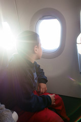 Boy looking outside of airplane window
