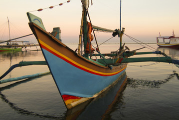 Fototapeta premium Balinese Fishing Boats Anchored in the Village of Pemuteran. Balinese fishing boats, called jukung, in the bay of northwest Bali, Indonesia during a beautiful sunrise. 