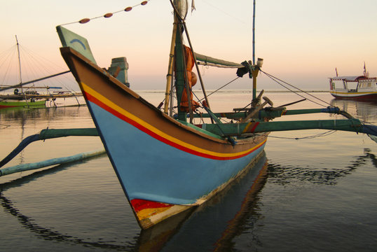 Balinese Fishing Boats Anchored in the Village of Pemuteran. Balinese fishing boats, called jukung, in the bay of northwest Bali, Indonesia during a beautiful sunrise. 