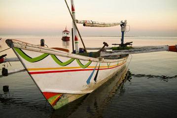 Fototapeta premium Balinese Fishing Boats Anchored in the Village of Pemuteran. Balinese fishing boats, called jukung, in the bay of northwest Bali, Indonesia during a beautiful sunrise. 
