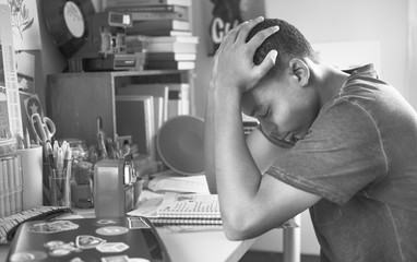 Teenage boy in a bedroom doing work stressed out and frustrated